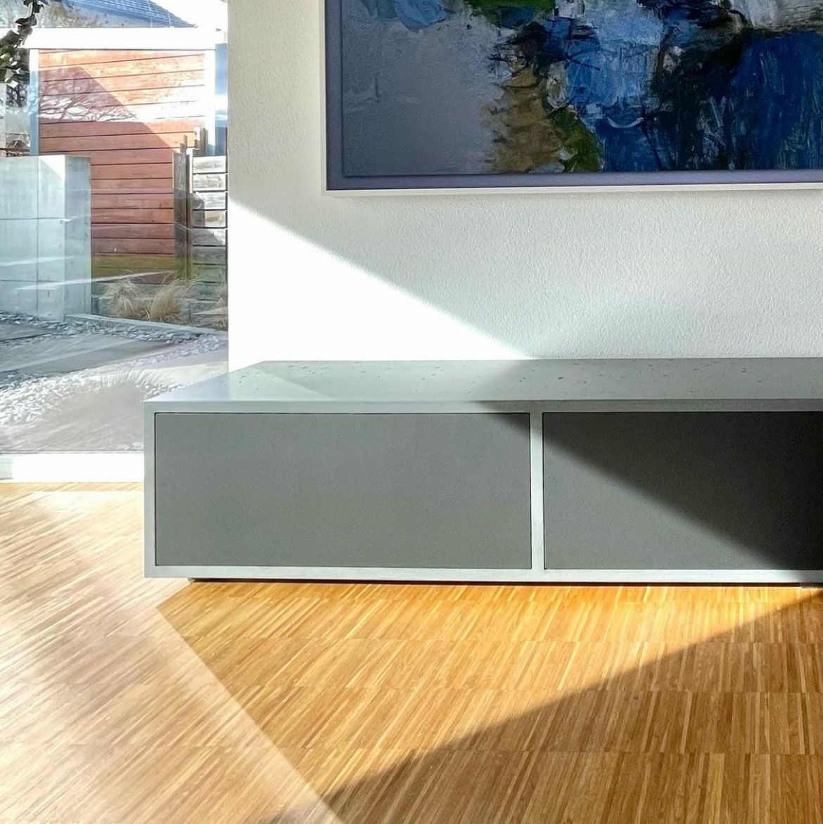 Tiefes Beton-Lowboard mit dunkeln Fronten aus Fenix